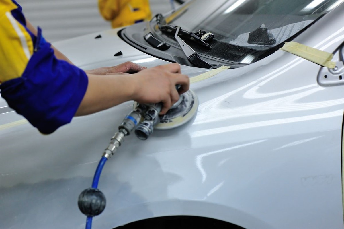 A person waxing the car with an equipment